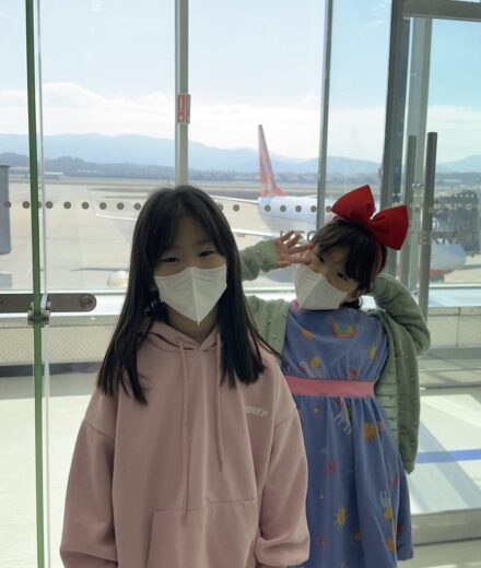 Two daughters waiting for their first flight beside an airport window
