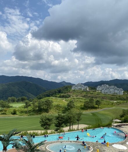 The infinity pool below green hills and resort buildings at Sono Felice Village Vivaldi Park